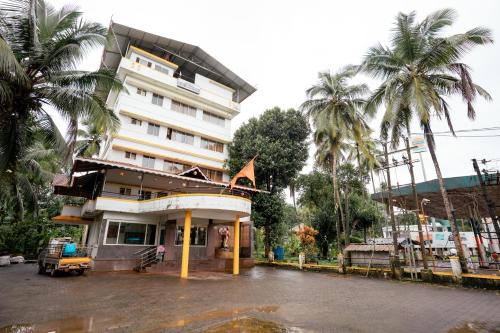 a building with palm trees in front of it at Kukke Sai Skanda in Subrahmanya