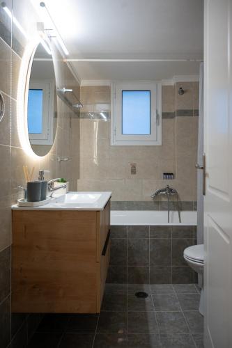 a bathroom with a sink and a tub and a toilet at Pnoé Luminous Apartment in Nafplio