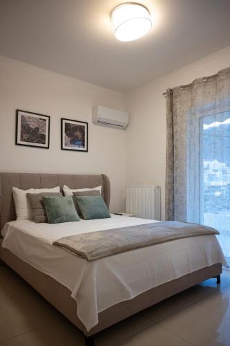 a bedroom with a large bed and a window at Pnoé Luminous Apartment in Nafplio