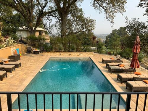 a swimming pool with chairs and umbrellas at Country Club Living on Golf Course & amazing views in Pleasanton