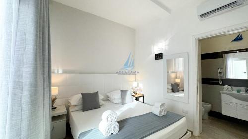 a white bedroom with a bed and a mirror at AQUARAMA Rooms & Apartments in Torre Squillace
