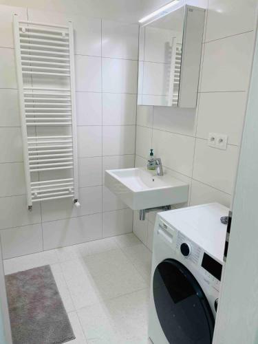 a white bathroom with a washing machine and a sink at Moruse airport apartment in Prievoz