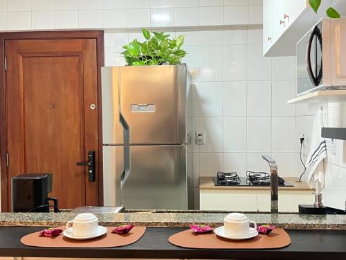 ベレンにあるComfortable 2BR Apt in Belém Best Areaのステンレス製の冷蔵庫とカウンターに帽子が2つ置かれたキッチン