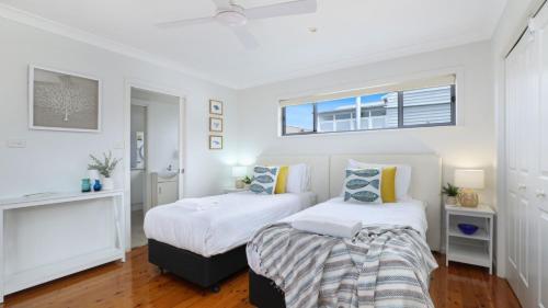 two beds in a room with white walls and a window at Rockpool Retreat in Currarong
