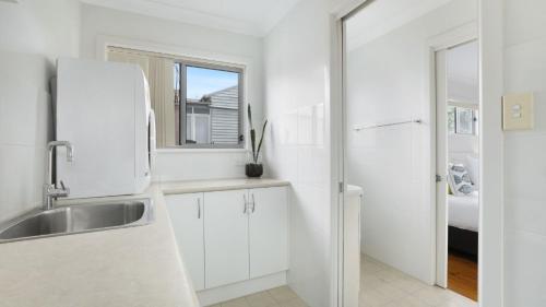 a white kitchen with a sink and a refrigerator at Rockpool Retreat in Currarong