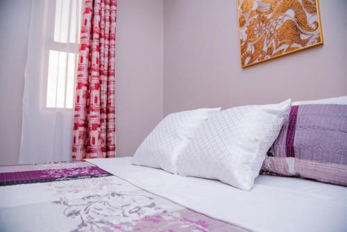 a white bed with a pillow and a window at The House in Kampala
