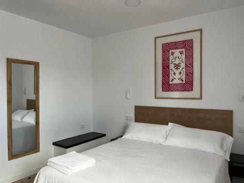 una camera da letto con un letto bianco e uno specchio di Tres Olivos a La Alberca