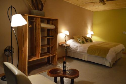 a bedroom with a bed and a table with a bottle of wine at Aldea de los Cerros in Yacanto