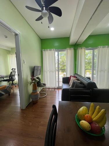 a living room with a table with a bowl of fruit on it at 1BR Condo w Pool & Balcony Near Robinson Place - F&M Homes - Sitio Uno Residences, Pueblo de Panay in Roxas City