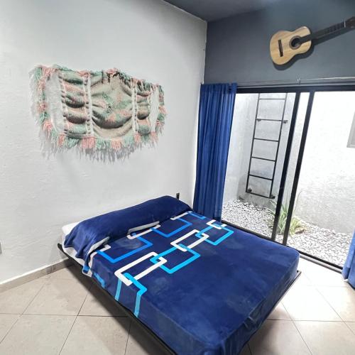 a bedroom with a bed with blue sheets and a window at Casa con alberca en Morelos in Barranca Honda