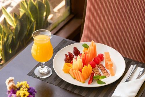 a plate of fruit and vegetables and a glass of orange juice at Marriott Venezuela Hotel Playa Grande in Playa Grande