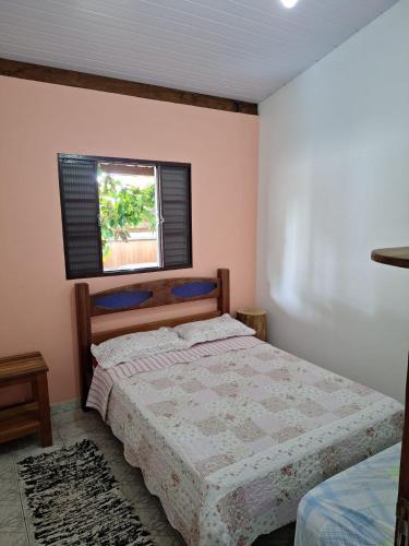 a bedroom with a bed and a window at Casa entre a praia do Curral e cachoeira in Ilhabela