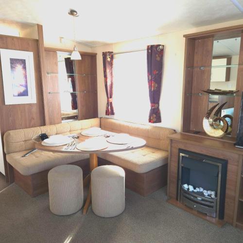 a living room with a table and a fireplace at Coastal Retreats in Great Clacton