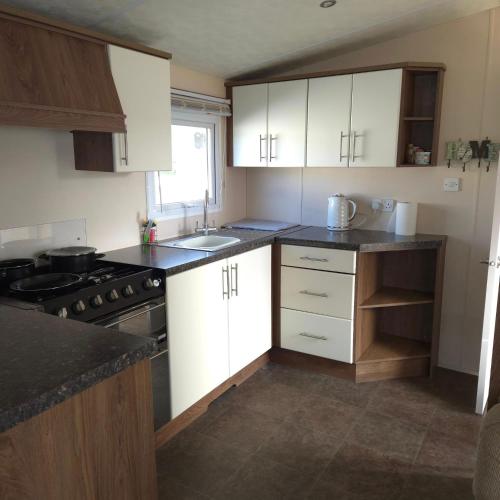 a kitchen with white cabinets and black counter tops at Coastal Retreats in Great Clacton