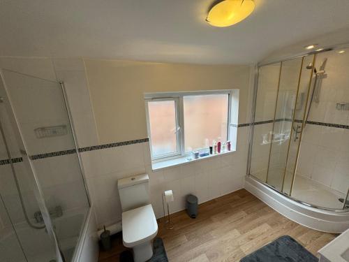 een badkamer met douche en toilet en een raam bij Quarto privativo em uma casa com outros quartos e banheiro compartilhado in Peterborough
