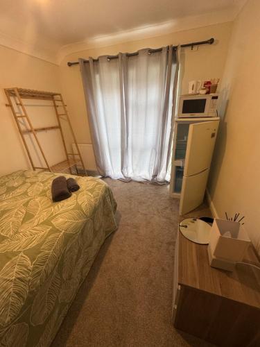 een slaapkamer met een bed, een magnetron en een raam bij Quarto privativo em uma casa com outros quartos e banheiro compartilhado in Peterborough