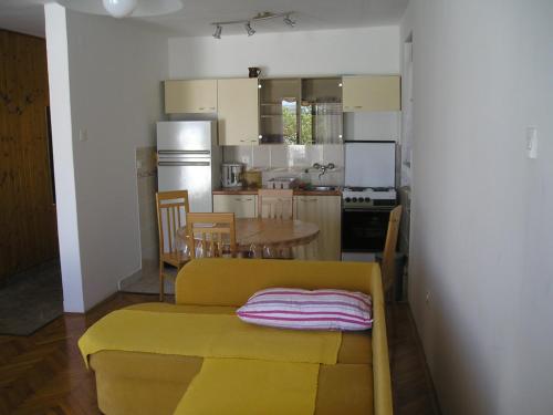 a kitchen with a yellow couch and a table in it at Apartment Any in Selce