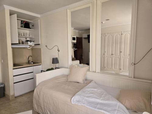 a white bedroom with a bed and a mirror at Anastacia Studio in Arguineguín