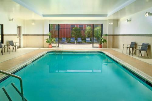 a pool in a hotel room with chairs and tables at Courtyard by Marriott Carrollton in Carrollton