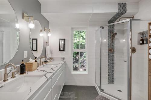 a white bathroom with two sinks and a shower at Hood Canal Escape- upscale meets the rocky shores! in Belfair