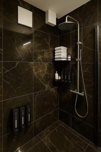 a bathroom with a shower with black tiles at Lux Line Apartment in Zürich