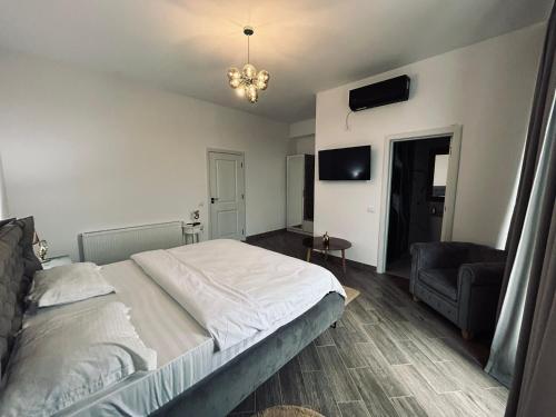 a bedroom with a large bed and a chair at Pensiunea Gloria in Afumaţi
