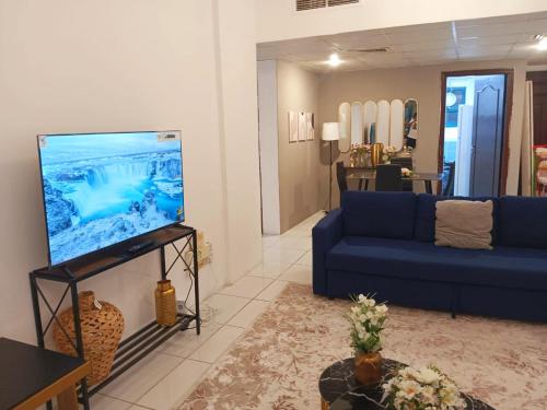 a living room with a blue couch and a tv at Beautiful 3-bedroom Apartment in Sharjah