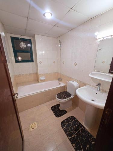 a bathroom with a tub and a toilet and a sink at Beautiful 3-bedroom Family Apartment near Buhaira Corniche in Sharjah