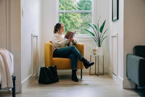 eine Frau, die auf einem Stuhl sitzt und ein Buch liest in der Unterkunft The Key Reno'd Historic Studio 1 Mile to UF & DT in Gainesville