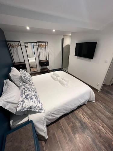 a bedroom with a large white bed and a flat screen tv at Chez Fil'O in La Bouille
