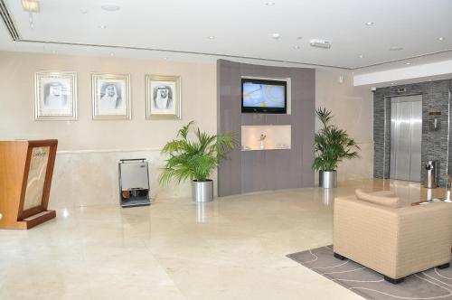 a lobby with a tv and plants in a room at Phoenix Plaza Hotel Apartments in Abu Dhabi
