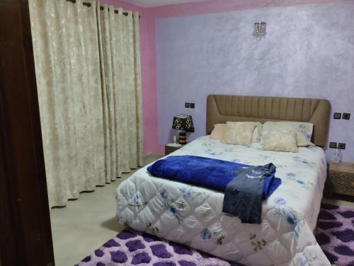 une chambre avec un grand lit avec une couverture bleue dans l'établissement Villa, à Meknès