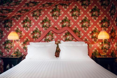 a bedroom with a white bed with a red wall at Maison Athénée in Paris