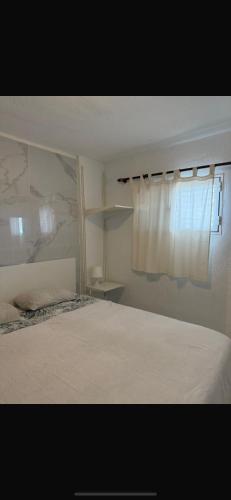 a bedroom with a white bed and a window at Residence Los Molinos in Maspalomas