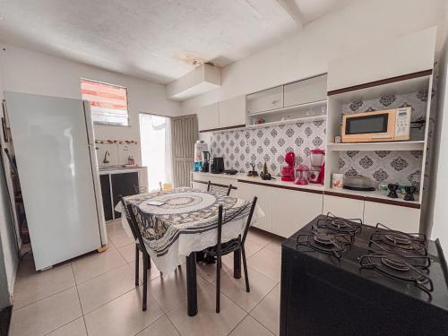 a kitchen with a table and a refrigerator and a stove at Quarto privativo La Paz in Aracaju