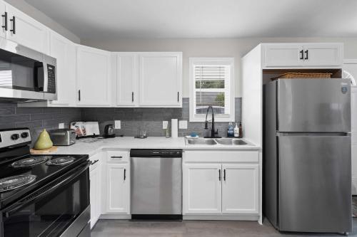 Una cocina con gabinetes blancos y un refrigerador de acero inoxidable. en 7 Min walk to Golden Belt - 4 Min Drive to Downtown - 7 to Duke, en Durham