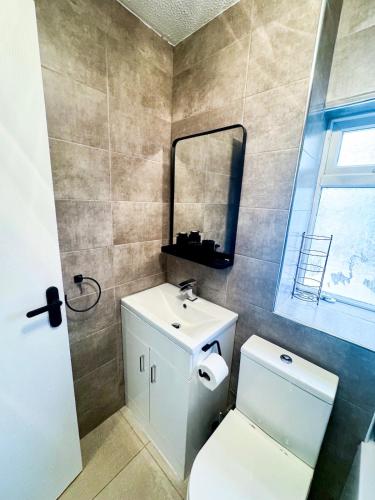 a bathroom with a toilet and a sink and a mirror at Modern 2-Bed w Parking & Garden in Woolwich