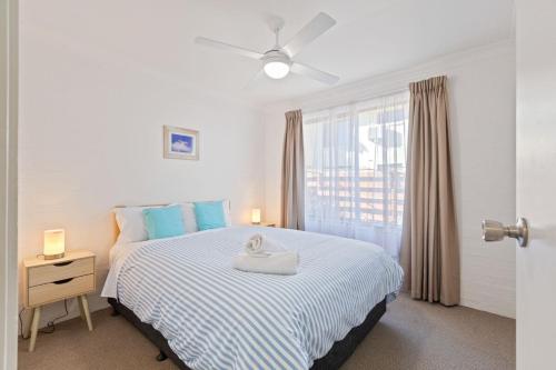 a bedroom with a large bed with blue pillows at The Sand Nook - 2 Bedroom Fishpen Apartment in Merimbula