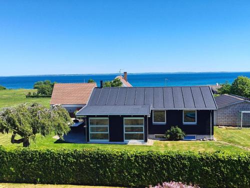 a house with a black roof and the ocean in the background at 6 person holiday home in Augustenborg in Augustenborg