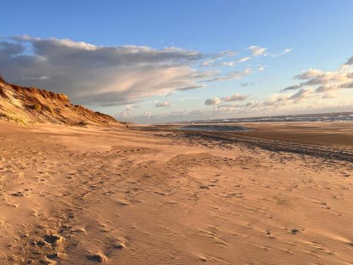 een zandstrand met voetafdrukken in het zand bij Rustic Retreat with View - By Traum Ferienwohnungen in Søndervig