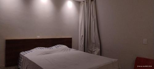 a bedroom with a bed with a white sheets and a window at Pousada horbis in Guarabira