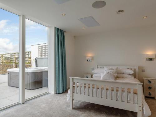 a white bedroom with a bed and a balcony at 5 Bed in Polruan 77657 in Polruan