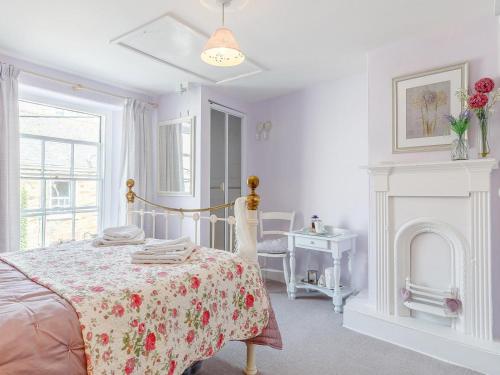 a white bedroom with a bed and a fireplace at 3 Bed in Polruan PC012 in Polruan