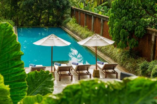 a group of chairs and umbrellas next to a pool at Tamarind Hill Galle in Galle