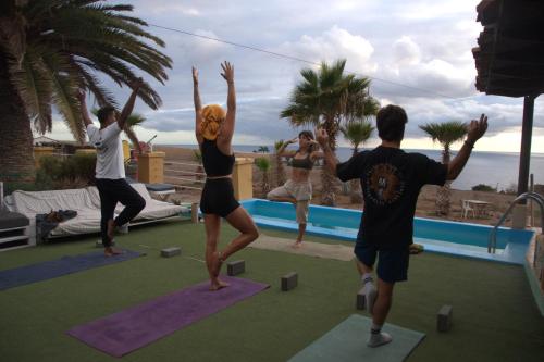 a group of people doing yoga by a pool at The Tree House Camp in Adeje