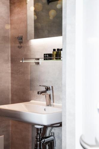 a bathroom with a white sink and a mirror at Lägenhetshotellet Fridhem in Krylbo