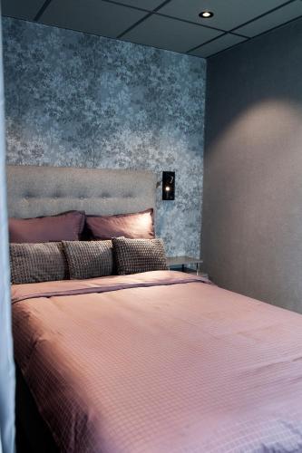 a bedroom with a large bed with pink sheets at Lägenhetshotellet Fridhem in Krylbo