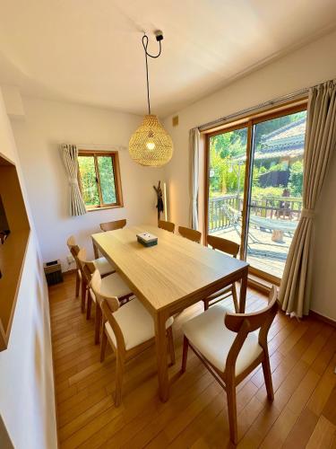 a dining room with a wooden table and chairs at イヌサウナリゾート伊豆白浜 愛犬と焚火とバレルサウナの暖かいヴィラ in Shimoda