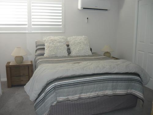 a bedroom with a bed with pillows and a window at Oscar's at Banora in Kurrara