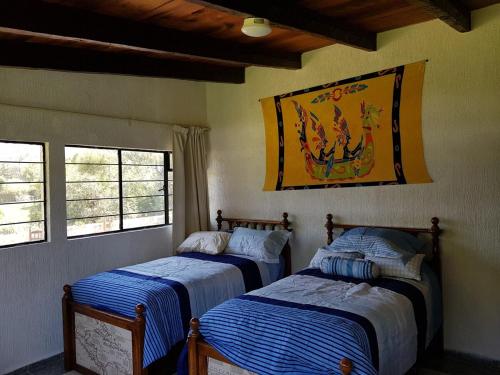zwei Betten in einem Zimmer mit einem Gemälde an der Wand in der Unterkunft Casa Grande, Casita, Gran Jardín, Juegos para 19 personas en el Pueblo in Valle de Bravo